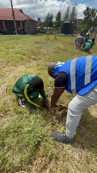 A member helps a learner plant a seedling